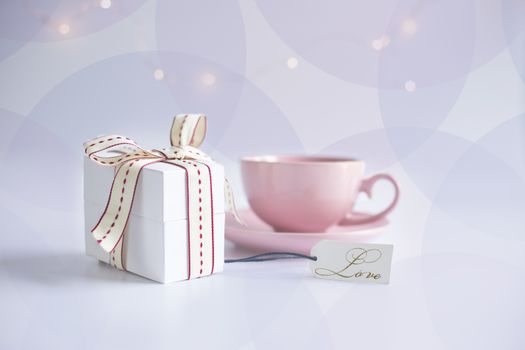 Pink porcelain cup of tea coffee and gift tug with word LOVE on white background with circles. Card, poster, mock up. Celebrating, love, anniversary, birthday, valentins concept.