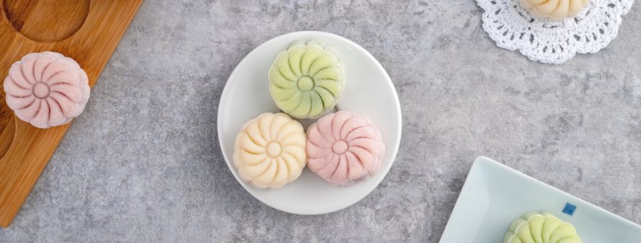 Colorful snow skin moon cake, sweet snowy mooncake, traditional savory dessert for Mid-Autumn Festival on gray cement background, top view