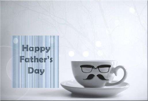 Cup of morning coffee tea with icons of mustache and eyeglasses and greeting card with word Happy Fathers Day on light background with bokeh.