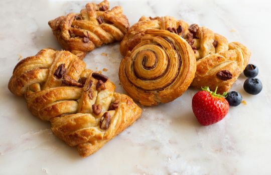 selection of French, Danish pastries with summer fruits on white marble background. Breakfast, morning treat, continental cafe