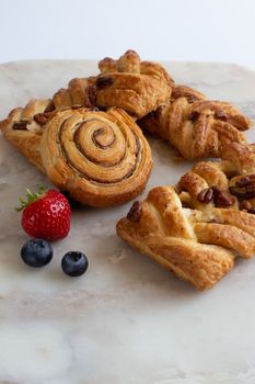 Selection of French, Danish pastries with summer fruits on white marble background. Breakfast, morning treat, continental cafe