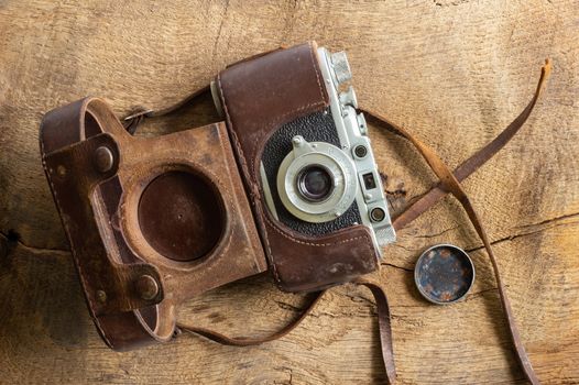 Ancient old vintage film camera with old lether cover on brown old wood background. Antique, vintage, grunge, classic concept