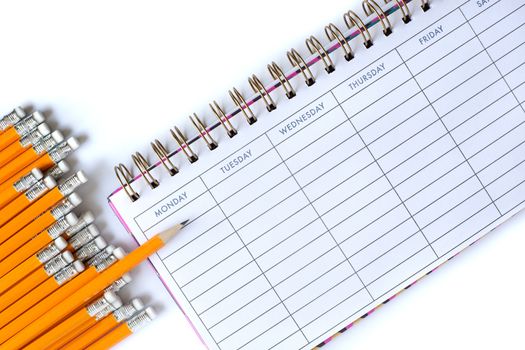 Stationery flat lay. Weekly organizer planner, sharp pencil surrounded by dull pencils. Stationery flat lay. Back to school. White background. Business, sharp idea concept