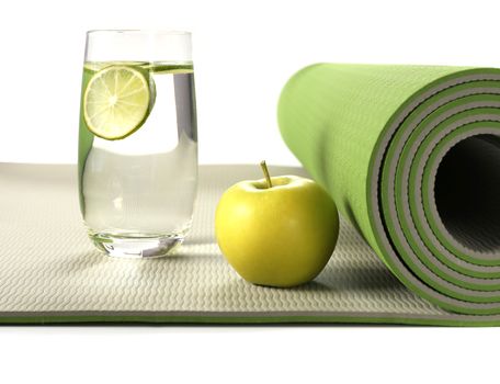 Green yoga mat with apple and glass of water with lemon on white background, Healthy life concept