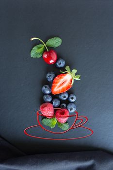 Summer fruits, berries and mint in chalk painted cup of tea on black background. Conceptual healthy, vitamin, dietary food. Vegan, vegetarian and detox food and drinks. Menu mock up for cafe, poster concept