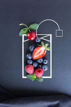 Summer fruits, berries and mint in icon of tea bag and green leaf on black background. Healthy, vitamin, dietary food. Vegan, vegetarian, detox food and drinks. Menu mock up for cafe, poster concept