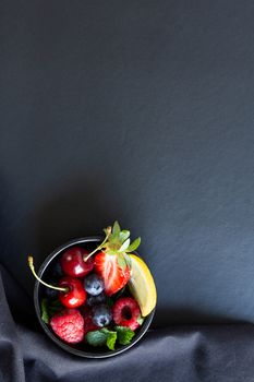 Summer fruits, berries and mint in chalk painted glass of juice on black background. Conceptual healthy, vitamin, diettary food. Vegan, vegetarian and detox food and drinks. Menu mock up, poster concept