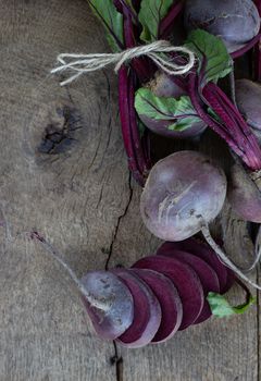 Bunch of fresh, spring, organic beetroot with slices of beetroot on old wooden background. Top view. Rustic, dramatic, organic kitchen. Ingredients, menu. Healthy life concept