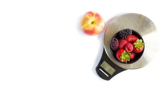 Black round plate with red black summer berries, apple and digital scale weight. Self weight control, diet, vegetarian concept