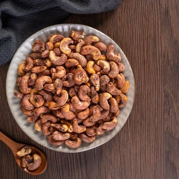 Cashew nuts with peel in a plate on wooden tray and table background, healthy raw food plate.
