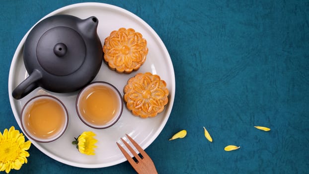 Moon cake for Mid-Autumn Festival, delicious beautiful fresh mooncake on a plate over blue background table, top view, flat lay layout design concept.