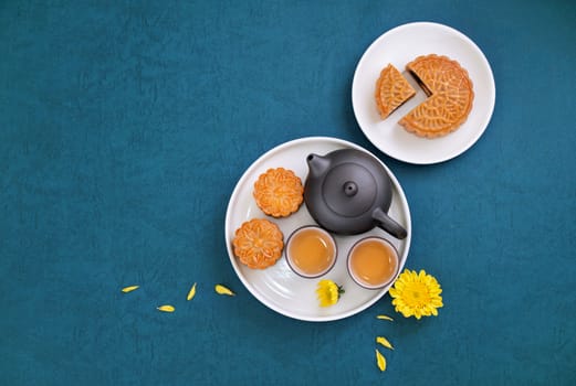 Moon cake for Mid-Autumn Festival, delicious beautiful fresh mooncake on a plate over blue background table, top view, flat lay layout design concept.