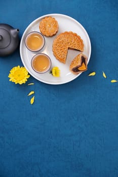 Moon cake for Mid-Autumn Festival, delicious beautiful fresh mooncake on a plate over blue background table, top view, flat lay layout design concept.