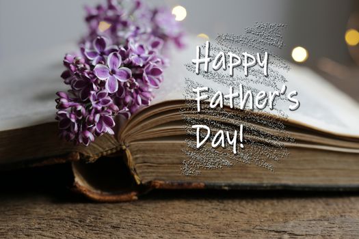 Words Happy Fathers Day open antique book with spring summer flowers, bokeh is on the background. Birthday greeting card concept