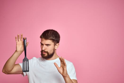 Man with spatula in hands kitchen accessories model emotions pink background cropped view Copy Space. High quality photo