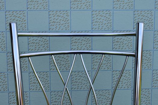 backrest of modern metal chair on vintage wallpaper background