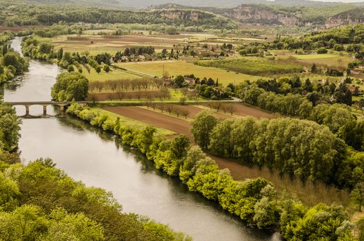 Dordogne river in the vicinity of the medieval village of Domme in the French department of Aquitaine, France, fields planted and mountains of calcareous rock formations common  in the area.