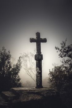 Shot of a beautiful religious stone cross on a foggy day