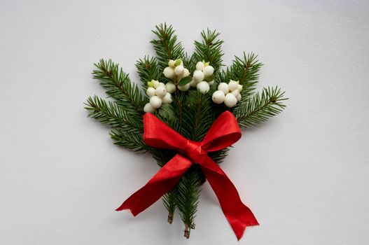 Christmas bouquet with fir branches, red bow and white dogwood berries on a white background . Christmas card. The theme of a winter holiday. Happy New Year.