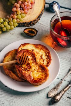 Healthy breakfast concept. French toasts with honey, fruits and tea over white wooden background