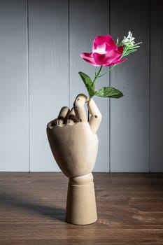 a flower held by a jointed wooden hand