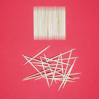 representation of order and disorder with toothpicks on a red surface