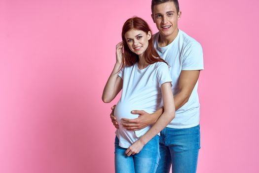 pregnant mom and happy father on pink background Young family waiting for baby. High quality photo