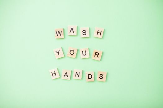 inscription from wooden blocks wash your hands on a light green background