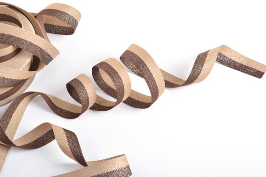Brown beige Cotton ribbon, roll textilies on bobbin. strapping tape with curl on white backgroud. Use for sewing clothes, bags. Space for text.