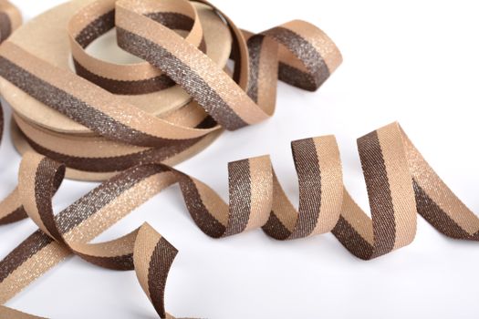 Brown beige Cotton ribbon, roll textilies on bobbin. strapping tape with curl on white backgroud. Use for sewing clothes, bags. Space for text.