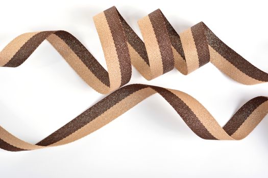 Brown beige Cotton ribbon, roll textilies on bobbin. strapping tape with curl on white backgroud. Use for sewing clothes, bags. Space for text.