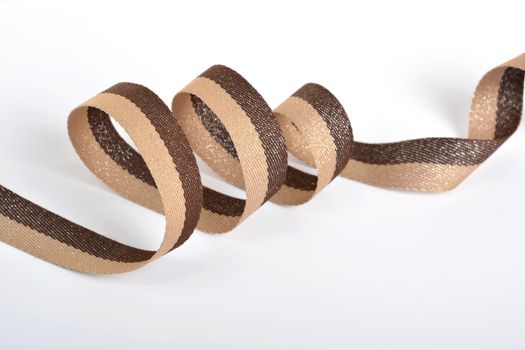 Brown beige Cotton ribbon, roll textilies on bobbin. strapping tape with curl on white backgroud. Use for sewing clothes, bags. Space for text.