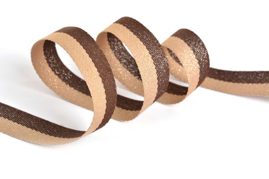 Brown beige Cotton ribbon, roll textilies on bobbin. strapping tape with curl on white backgroud. Use for sewing clothes, bags. Space for text.