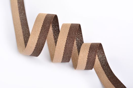 Brown beige Cotton ribbon, roll textilies on bobbin. strapping tape with curl on white backgroud. Use for sewing clothes, bags. Space for text.