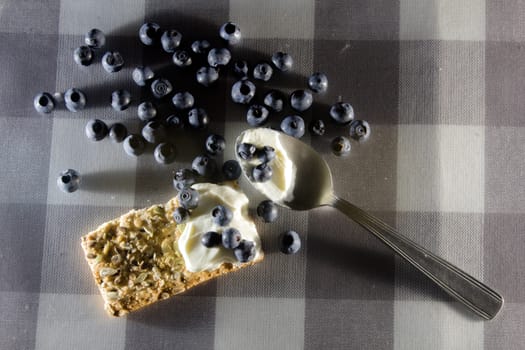 breakfast or snack made of cream on a cereals toast and some bilberries on the top