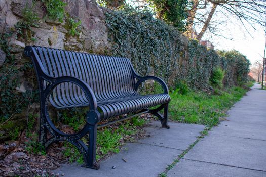 A Shaded Park Bench Against a Cobblestone Wall