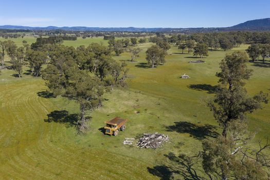 An aerial view of an old earthmoving truck in a lush green agricultural valley in regional Australia