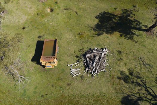 An aerial view of an old earthmoving truck in a lush green agricultural valley in regional Australia