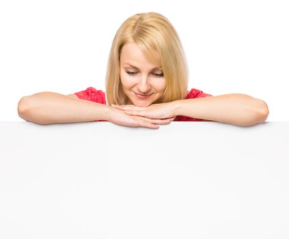 Portrait of happy smiling young woman, showing empty blank signboard with copyspace. Businesswoman holding big white banner, isolated on white background.