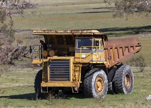 An old rusty earthmoving truck in a green field in regional Australia