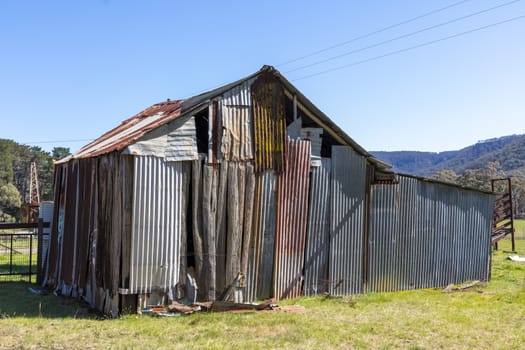 An old rusty shed and tanks in a green field in regional Australia