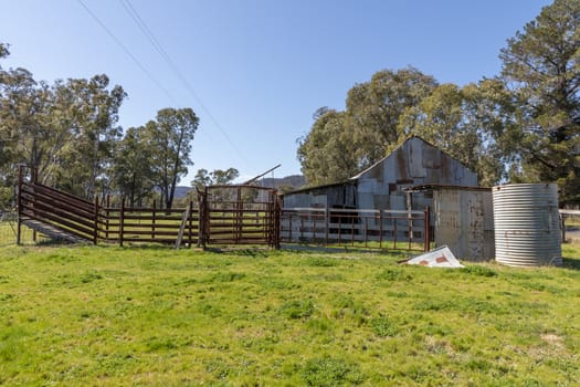 An old rusty shed and tanks in a green field in regional Australia