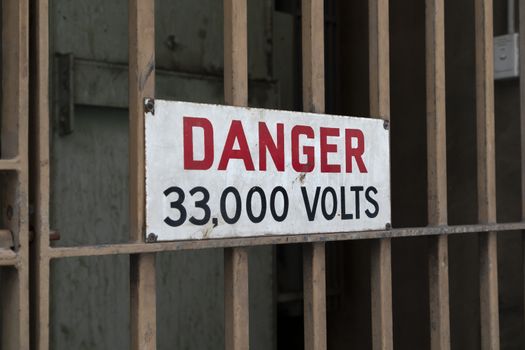 Electricity safety danger sign on a locked metal gate