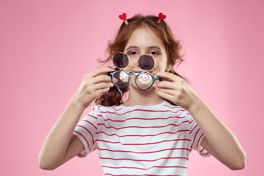 Cheerful girl with pigtails sunglasses striped t-shirt lifestyle pink background. High quality photo