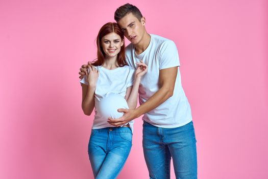 pregnant mom and happy father on pink background Young family waiting for baby. High quality photo