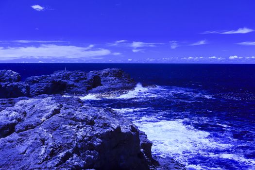 The ocean crashing on rocks with white waves in Kiama New South Wales taken in Infrared