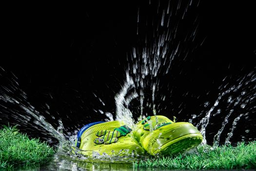 Shoes, water and green grass on a black background