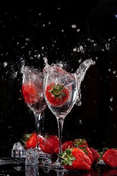 Strawberry falling into the glass with water