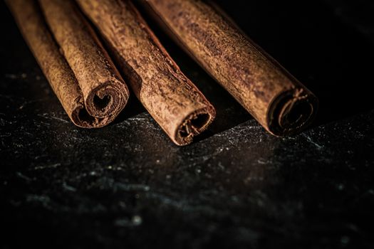 Cinnamon sticks on black stone background, food recipes