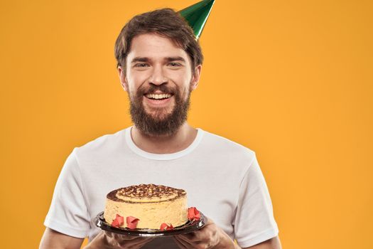 A bearded man with a cake and in a cap celebrating his birthday. High quality photo
